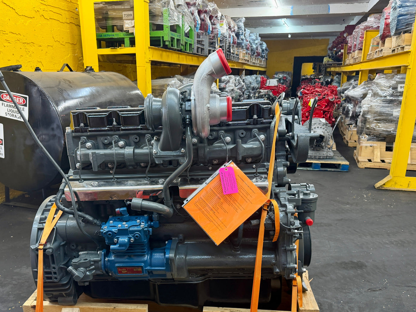 Large industrial Mack Diesel engine on a wooden pallet in a warehouse setting